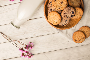 Chocolate chip cookies with milk on burlap and rustic wooden table