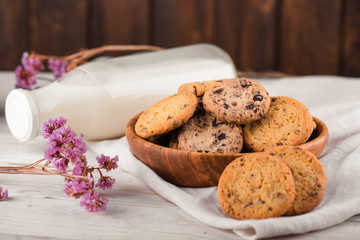 Chocolate chip cookies with milk on burlap and rustic wooden table