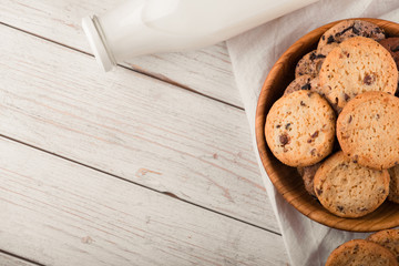 Chocolate chip cookies with milk on burlap and rustic wooden table