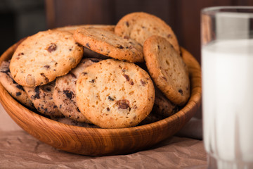 Chocolate chip cookies with milk on burlap and rustic wooden table