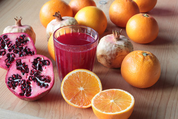 pomegranate and orange juice near fruits cut in half