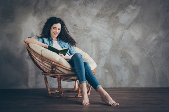 Portrait of her she nice attractive lovely winsome charming cheerful cheery focused wavy-haired girl sitting in chair reading novel paper book at modern loft industrial style interior room