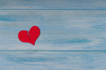Red broken heart on blue wooden background