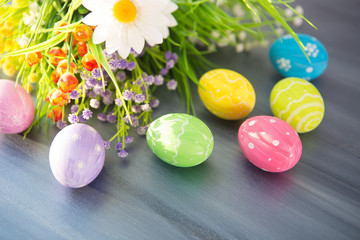 Fototapeta na wymiar Easter eggs and flowers on gray wooden planks
