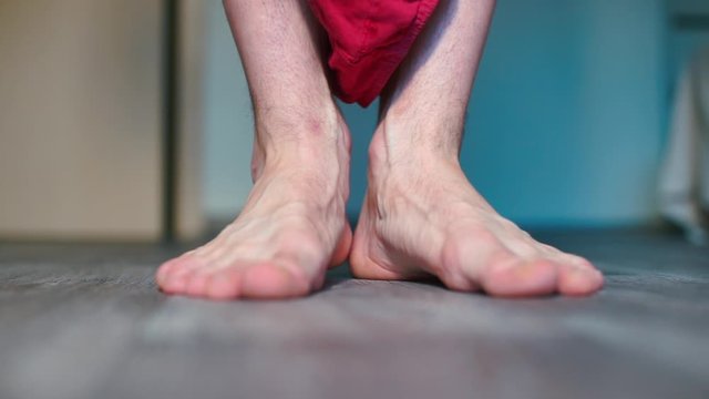 Close-up of male feet on the floor in a room.