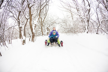 A woman with her son rides down the hill in a sleigh.