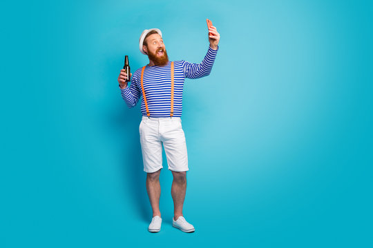 Full body photo of crazy redhair beard man have holiday relax blogging make selfie show his bottle beer wear orange suspenders white shorts sun headwear isolated blue color background