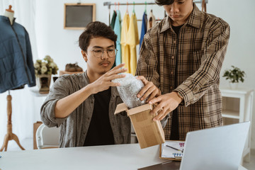 Obraz premium two young Asian workers work together to pack camera lenses in the office