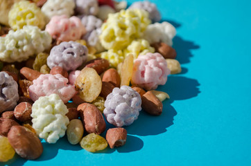 Assorted of sugared dried fruits, nuts and dragees in sugar, on a blue background with copyspace