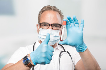 doctor mit medical face mask and medical gloves shows a blood probe and shows thumbs up