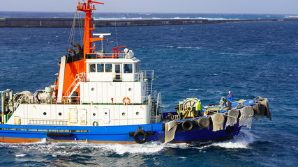 bright sea tug in the port of the Japanese city of Naha. Powerful industrial tugboat on a sunny day...