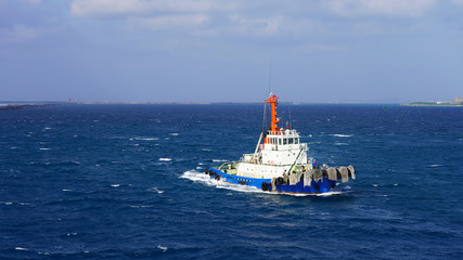 bright sea tug in the port of the Japanese city of Naha. Powerful industrial tugboat on a sunny day...