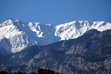 Landscape with Turkish mountains of different heights, mountain pines on the slopes and snow on high peaks at far