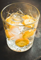 Old fahioned beverage with strong alcohol and kumquats on rustic background. Selective focus. Shallow depth of field.