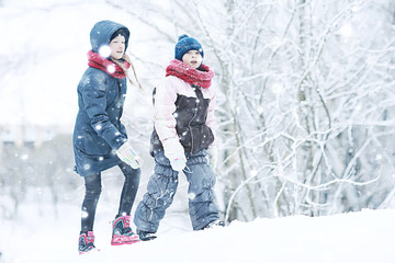 two sisters girls  winter for a walk / young girlfriends playing in the snow in the frost. The concept of childhood, friendship, family. Sports warm clothes, health immunity. Christmas morning.