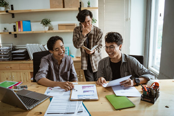 three young asian worker chatting about their product at work