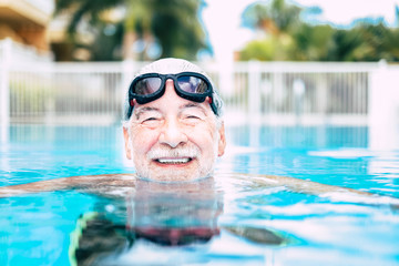 one mature man or senior at the swimming pool looking at the camera smiling and having fun alone -...