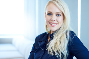 Portrait of a smiling young businesswoman sitting on a sofa in a modern office