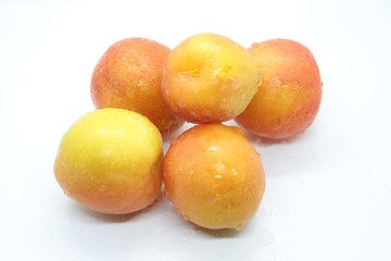 Ripe wet yellow plums located on a white background