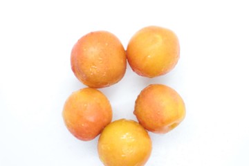 Ripe wet yellow plums located on a white background