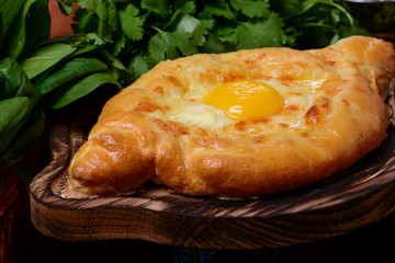 Georgian traditional cuisine. Ajarian traditional flatbread khachapuri. Open pie with mozzarella cheese and egg