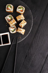 Traditional Asian cuisine sushi rolls on a black wooden table