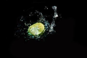 Fototapeta na wymiar Lemon slice into the water until the sponge splits beautifully on a black background.