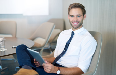 Stylish young businessman in modern space smiling with tablet