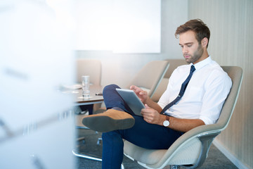 Modern young businessman using digital tablet in meeting room