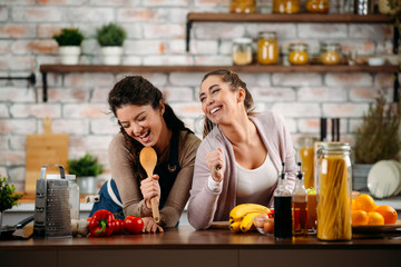 Two friends having fun in kitchen. Sisters cooking together.