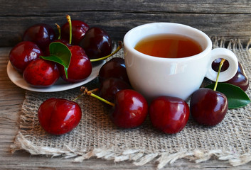 Cherry fruit tea with freshly picked cherries in a white cup on a burlap cloth.Selective focus