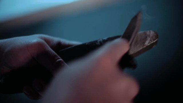 A man is sharpening a knife on a grindstone close-up.