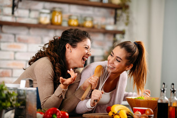 Two friends having fun in kitchen. Sisters cooking together.