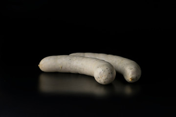 Two long white raw bratwurst sausage isolated on black background