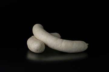 Two long white raw bratwurst sausage isolated on black background