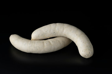 Two long white raw bratwurst sausage isolated on black background