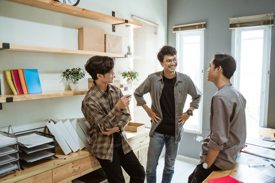 Three Young Asian Businessman Chatting About Their Product At Work