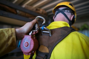 Male construction worker hand clipping locking carabiner which connecting with self retractable...