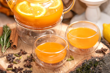 Sea Buckthorn tea candle basking in Russian restaurant. Vitaminic healthy sea buckthorn tea with cinnamon, lemon, rosemary, honey on wooden background.