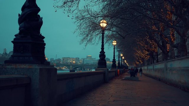 People walking alongside the River Thames in London during evening