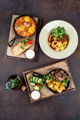 Several dishes in pans with meat, potatoes, vegetables
