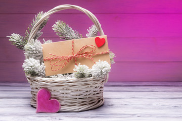 Fototapeta na wymiar Valentine's day concept with envelope in basket over pink wooden background