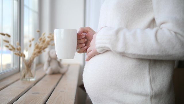 Closeup Of Pregnant Woman With Cup Drinking Tea In The Morning