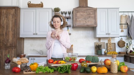 Pregnant Woman Cooking Healthy Food On Kitchen And Using Smartphone.