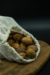 Close up view of eco friendly reusable cotton string bag open full of nuts, on a wooden table. Zero waste concept.