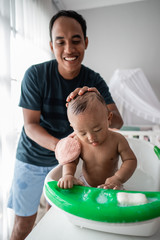 father enjoy wash her baby boy at home in the basin