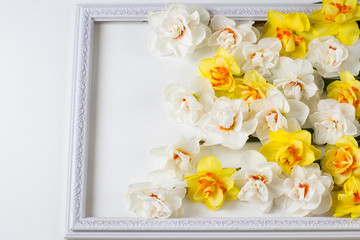 Fototapeta na wymiar a white openwork frame a bouquet of yellow and white daffodils