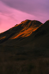 Beautiful scenic sunset in Iceland. Yellow lit mountain side with pink clouds.