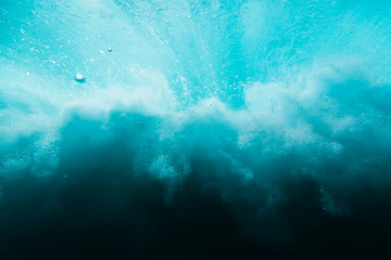 Wave with bubbles underwater. Transparent blue ocean in underwater