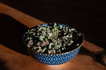 Dried oregano in a bowl on a wooden table